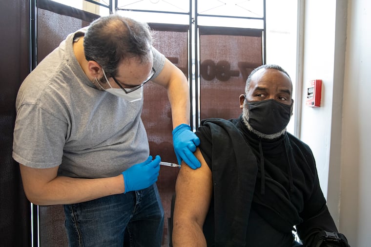 David Parker, of West Philadelphia, receive his first shot by pharmacist Ben Nachum, at Patriot Pharmacy on March 17.