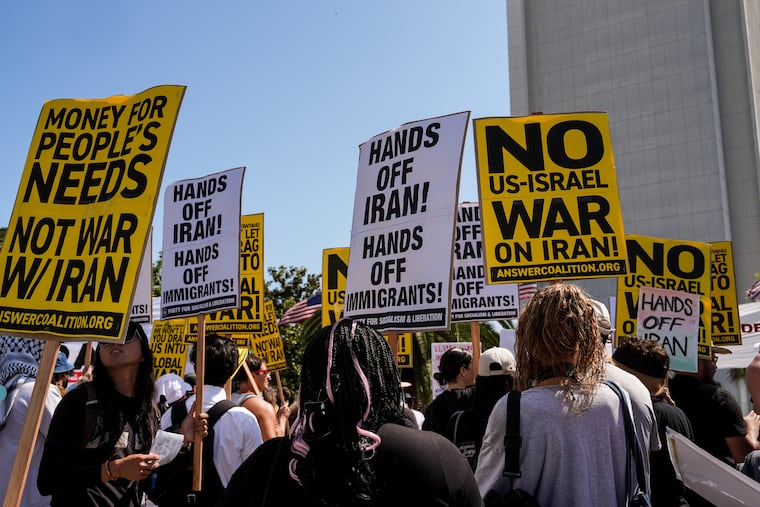 Anti-war demonstrators hold signs outside the Wilshire Federal Building in Los Angeles on Sunday following U.S. airstrikes on Iran's nuclear facilities.