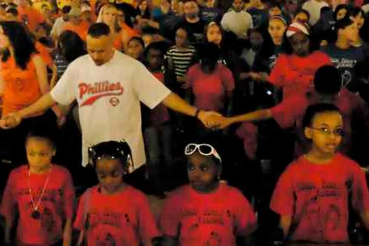 John Coleman holds hands with children from the St. Martinde Porres school before the Hands Across Lehigh march. The annual event began at St. Martin's with a program including prayers and a reading of names of local victims of violence.