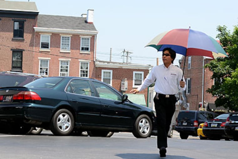Carrying his own shade, Medpark parking lot attendant Rimon Dorian of Glenolden works the hot asphalt in the lot off Gay Street in downtown West Chester. (Tom Gralish / Staff Photographer)