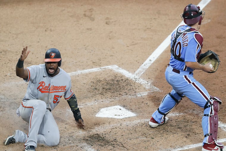 Baltimore's Hanser Alberto scores past Phillies catcher J.T. Realmuto during the fifth inning.