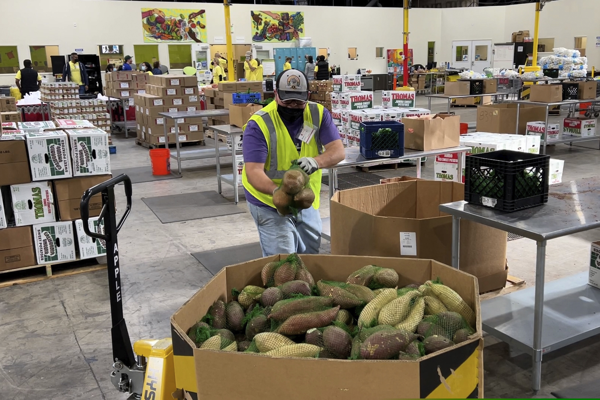 A worker puts bags of sweet potatoes in a container in the warehouse of the Alameda County Community Food Bank in Oakland, Calif., on Nov. 5, 2021. U.S. food banks dealing with increased demand from families sidelined by the pandemic now face a new challenge – surging food prices and supply chain issues. As holidays approach, some food banks worry they won't have enough turkeys, stuffing and cranberry sauce for Thanksgiving and Christmas. (AP Photo/Terry Chea)