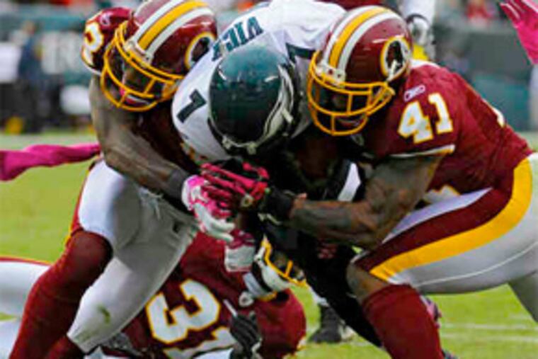 Eagles quarterback Michael Vick is smashed by Redskins DeAngelo Hall (left) and Kareem Moore. The first-quarter play ended Vick’s day. (Clem Murray / Staff Photographer)