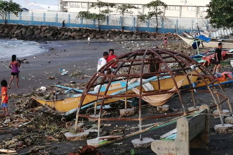 Residents walk beside an outrigger and playground equipment that were damaged by Typhoon Phanfone along a coastline in Ormoc city, central Philippines on Thursday. The typhoon left over a dozen dead and many homeless.