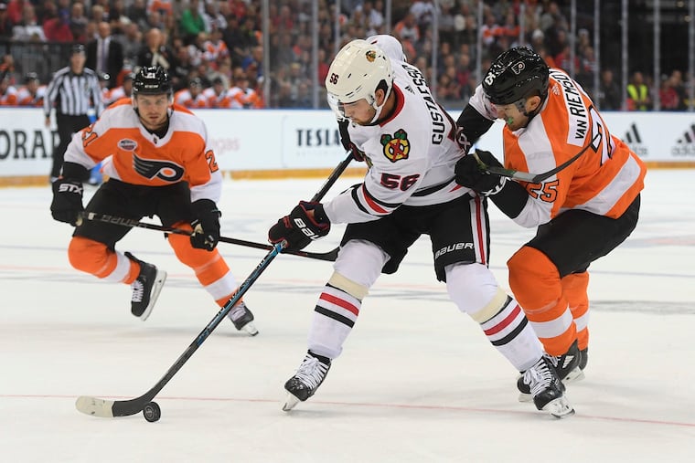 Erik Gustafsson (middle) and the Flyers' James van Riemsdyk (right) battle for the puck.