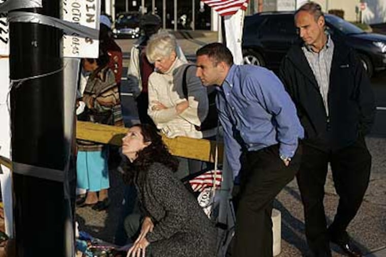 Family members visit a makeshift memorial in front of the Dunkin' Donuts on North Broad Street where Police Officer Chuck Cassidy was killed last week.