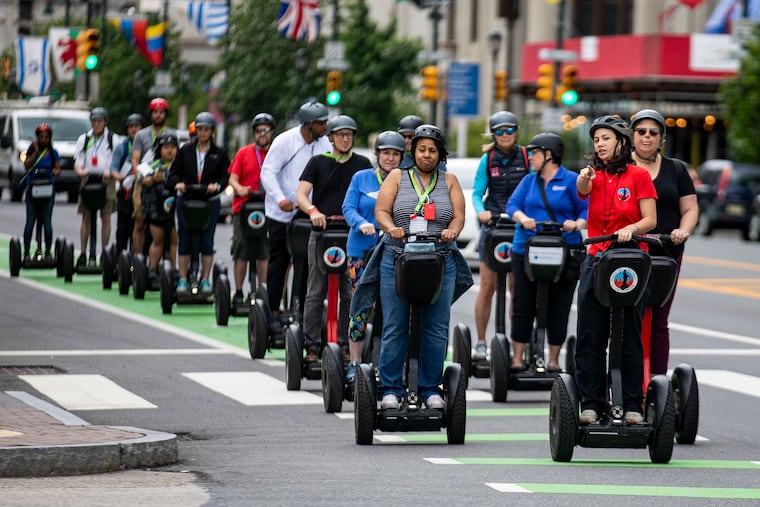 Sophia Rosser (red shirt), a Segway tour guide, leads a group of Greater & Greener conference attendees along the Benjamin Franklin Parkway on Saturday.