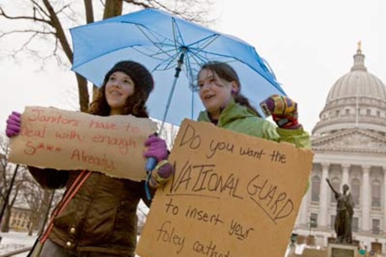Jane Moran, left, 14, and Emma Rankin-Utevsky, 14, protest outside of the State Capitol in Madison, Wisconsin on Sunday. Opponents to the governor's bill to eliminate collective bargaining rights for many state workers are on their sixth day of protesting. (AP Photo/Andy Manis)