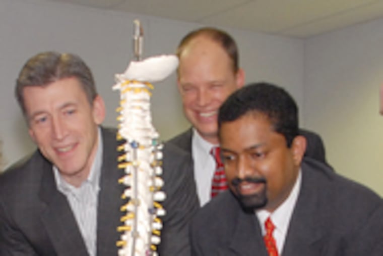 At Globus Medical (from left), Dave Demski, chief financial officer; Andy Iott, group manager; and David Paul, president and CEO, view a model with a sample implant attached. The company led in attracting venture capital in the last quarter.