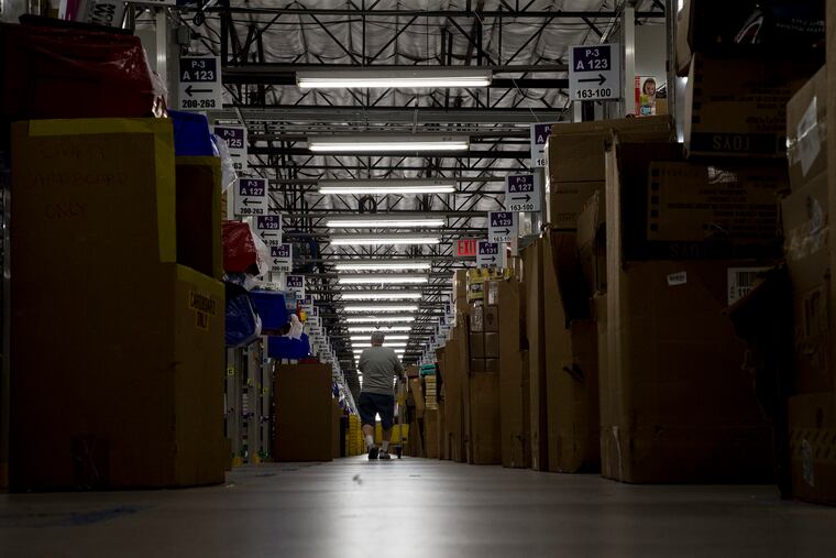 A worker filling an order pushes a cart through aisles of merchandise at an Amazon Fulfillment Center in San Bernardino. (Gina Ferazzi/Los Angeles Times/TNS)