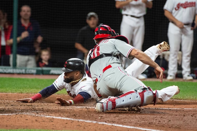 Cleveland's Carlos Santana slides safely home ahead of the tag by Phillies catcher J.T. Realmuto after a three-run double by Yasiel Puig in the seventh inning.