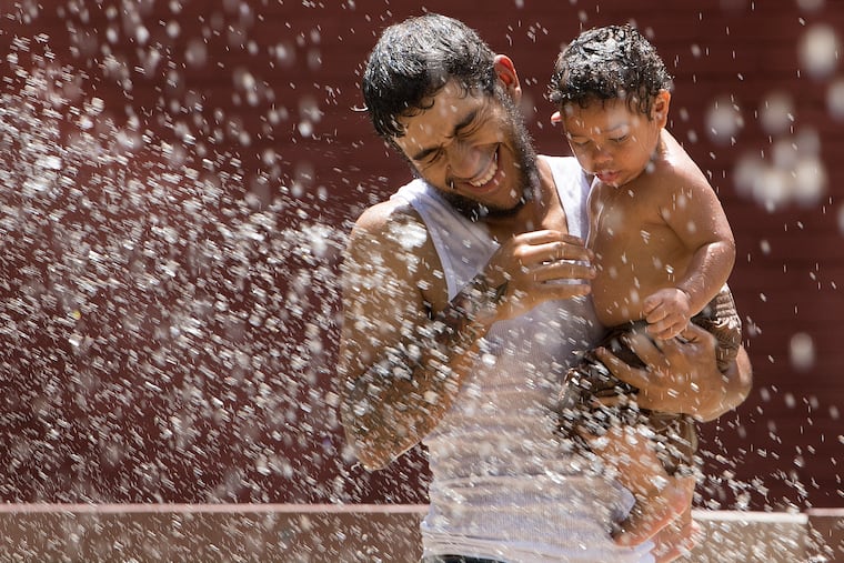 Angelo Rivera and his one-year-old son Angelo Jr. cool off at the at the Pyne Poynt Park water fountains in Camden on Thursday.