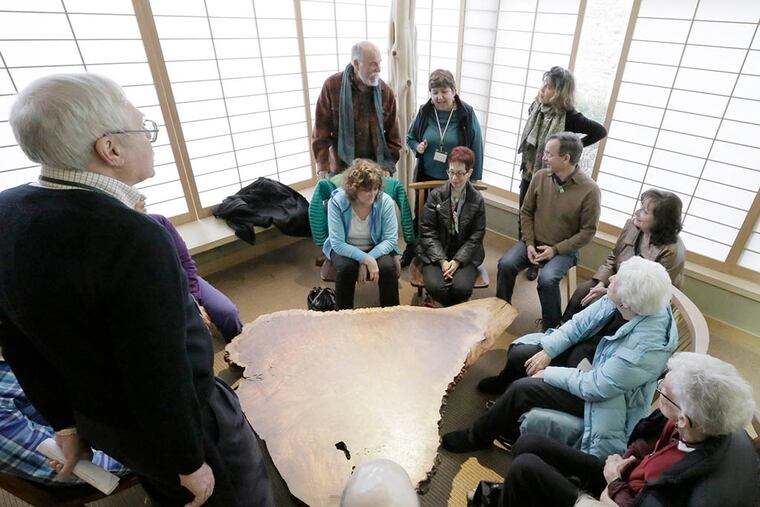 Museum docent Steve Wisniewski (in black sweater) tells visitors to touch as well as observe the table, as well as to close their eyes and reimagine the work. (ELIZABETH ROBERTSON / Staff Photographer)