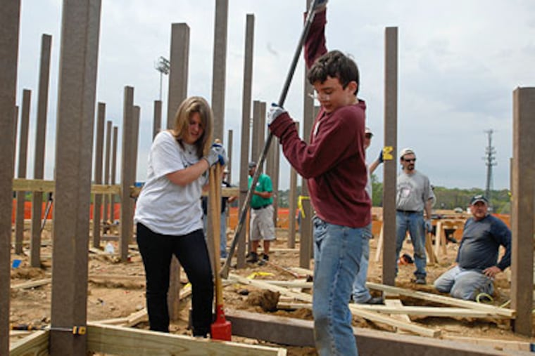 Evan Desantola knocks rocks loose in a post hole that Anna O'Neill was digging as part of the construction of Freedom Playground in Haverford Township. Both are sophomores at Lower Merion High School. (Ron Tarver / Staff Photographer)