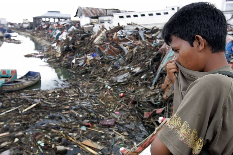 FILE - In this Saturday Jan. 1, 2005 file photo, a man looks at a floating debris and dead bodies on Aceh River in Banda Aceh, Indonesia. The tsunami that struck on Dec. 26, 2004, was one of the world’s worst natural disasters in modern times. The tsunami that struck on Dec. 26, 2004, was one of the world’s worst natural disasters in modern times. It followed a magnitude 9.1 earthquake that ruptured the sea floor off Indonesia’s Sumatra island, displacing billions of tons of water and sending waves 10 meters (33 feet) high radiating across the Indian Ocean at jetliner speeds. Associated Press journalists who covered the story recall some of the most poignant images from the disaster. (AP Photo/Eugene Hoshiko, File)