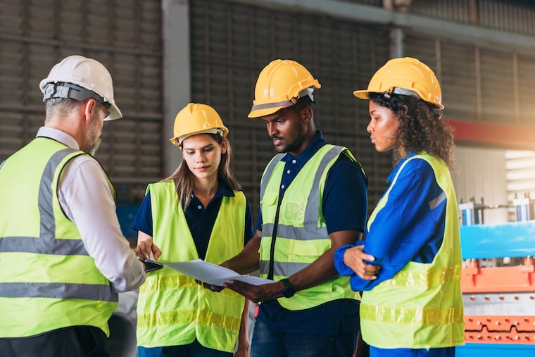 Engineers inspecting a machine at a factory as part of safety training.