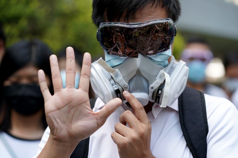 A protester wears a gas mask and holds up his hand to represent the protester's five demands in Hong Kong on Friday.