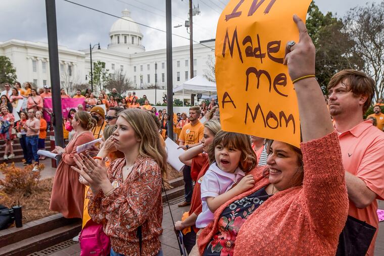 Veronica Wehby-Upchurch a sign and son Ladner Upchurch as hundreds gather for a protest rally for in vitro fertilization legislation Wednesday in Montgomery, Ala.