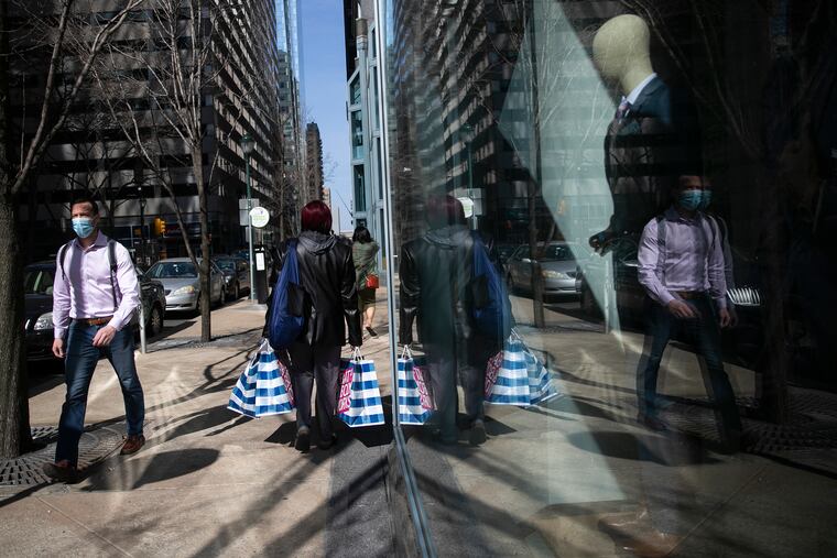 A pedestrian with shopping bags walks past a mannequin in a window at The Shops at Liberty Place in Center City Philadelphia. Puttshack, a miniature golf venue, is expected to open there later this month.