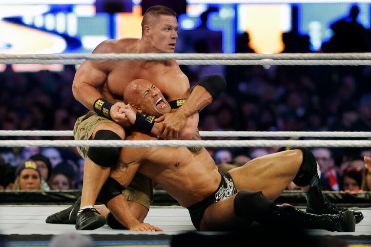 Wrestler John Cena, top, chokes Dwayne "The Rock" Johnson at a Wrestlemania event on April 7, 2013, in East Rutherford, N.J. It is a name that has become almost synonymous with professional wrestling but its bearer, Dwayne Johnson, has never legally owned "The Rock." (AP Photo/Mel Evans, File)