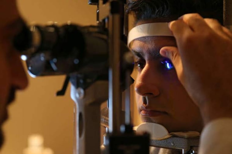 Wills Eye cornea surgeon Amir Azari (left) examines Akshay Patel, whose infection he diagnosed.