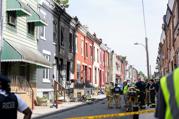 Firefighters at the scene of a house fire in Strawberry Mansion that killed a woman and two children.