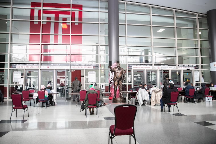 People wait to register for the COVID-19 vaccine in the lobby of the Liacouras Center in Philadelphia on Tuesday. The Black Doctors COVID-19 Consortium has been vaccinating Philadelphia residents who qualify.