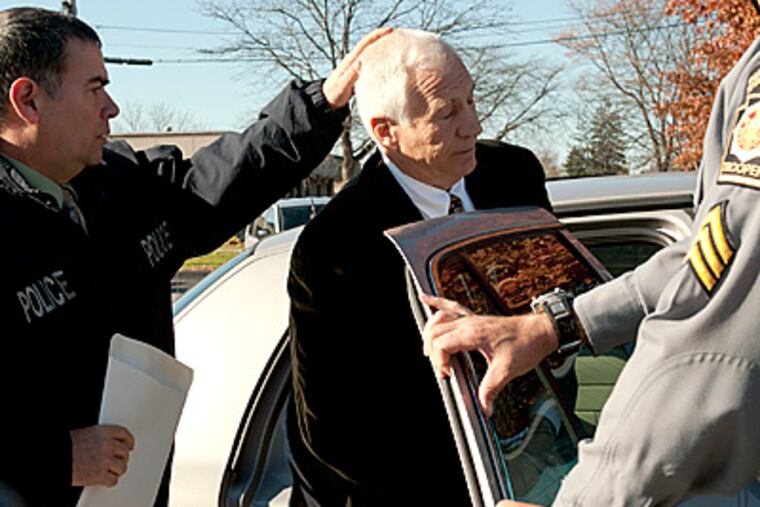 Former Penn State coach Jerry Sandusky is put in the back of a police car. (AP Photo/Pennsylvania Office of Attorney General)
