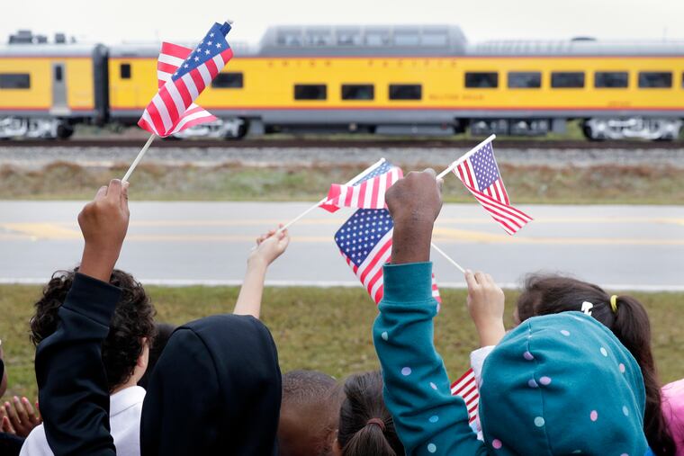 Students from Salyer Elementary School wave flags as the train carrying the body of former president George H.W. Bush travels past their school on the way to Bush's final internment Thursday, Dec. 6, 2018, in Spring, Texas. (AP Photo/Michael Wyke)