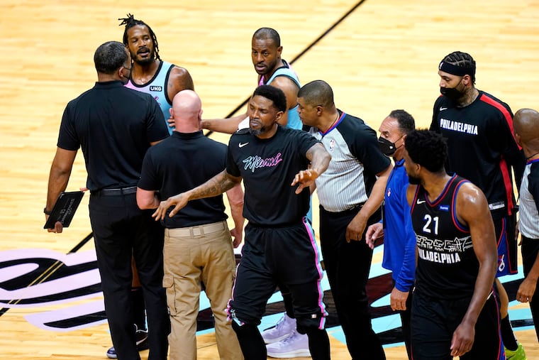 Miami Heat forward Udonis Haslem, center, who later got into it with Dwight Howard, separates Sixers center Joel Embiid (21) and Heat forward Trevor Ariza, left,during a tiimeout.