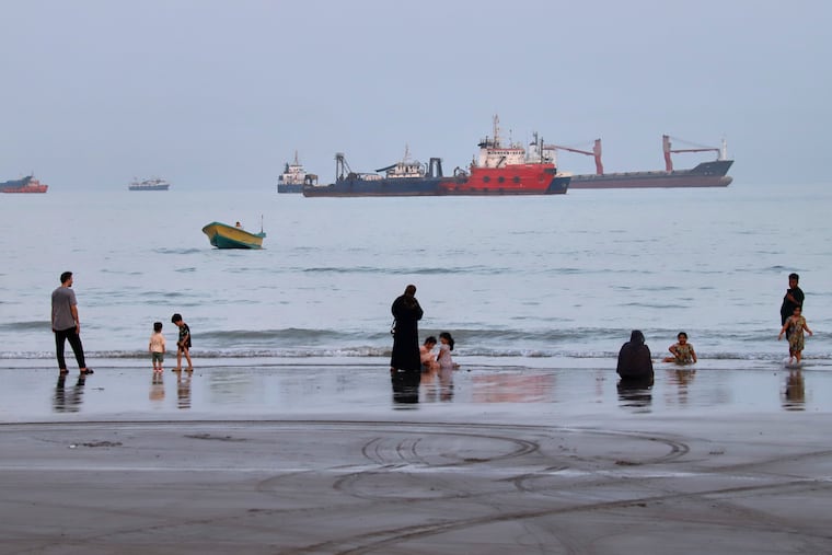 People spend time at a beach as commercial vessels are anchored in the Strait of Hormuz off Bandar Abbas, Iran, on Wednesday, Aug. 5.