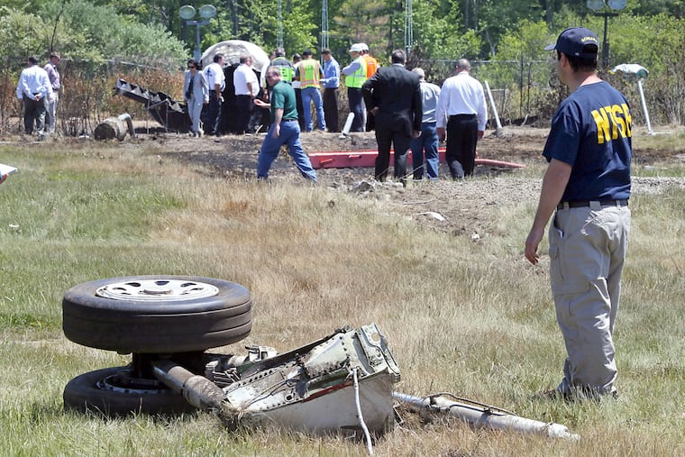 A National Transportation Safety Board official stands beside a piece of the landing gear where a plane crashed in June 2014 in Bedford, Mass., killing Lewis Katz, co-owner of Philadelphia Media Network, and six other people.