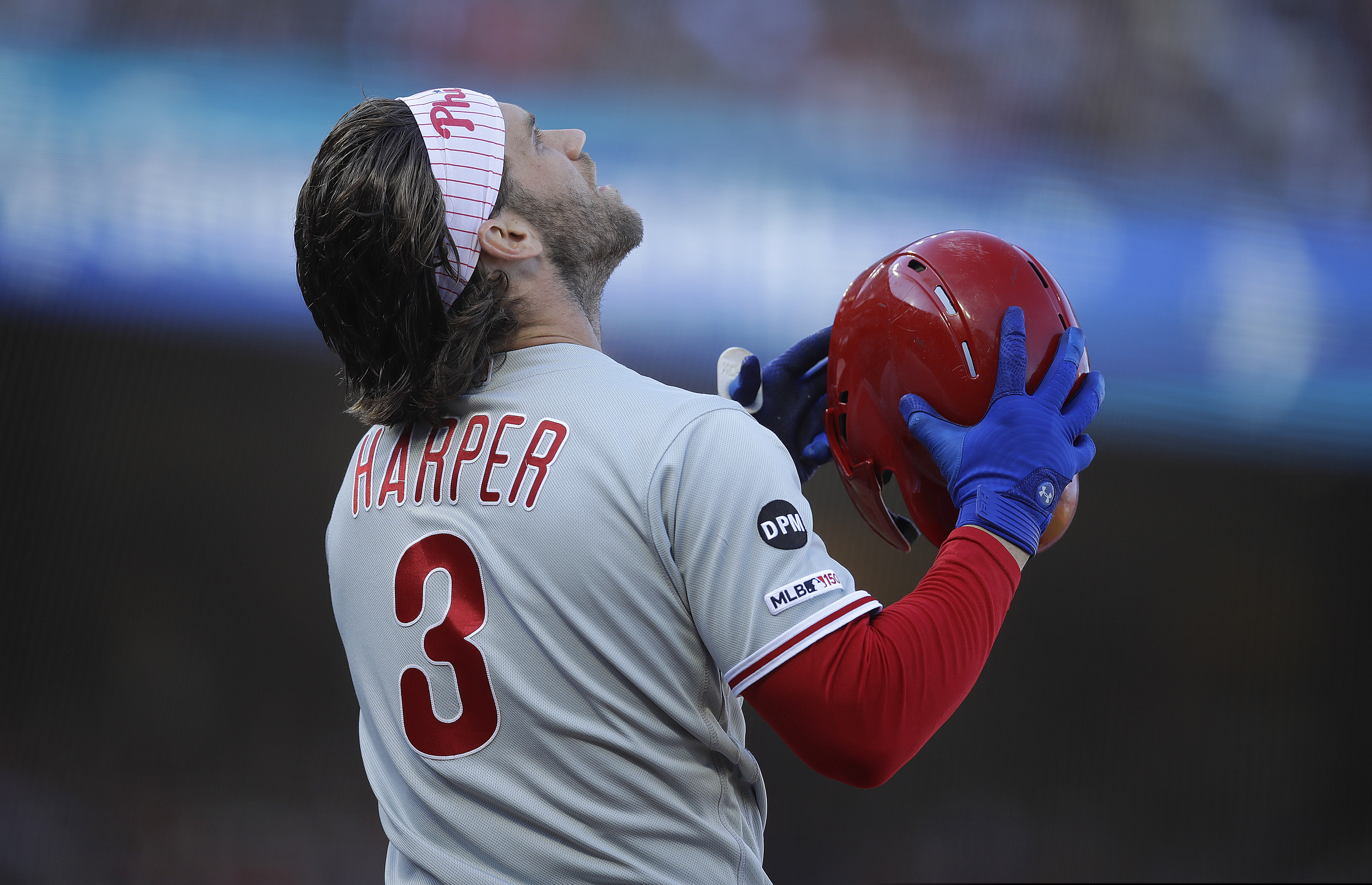 Bryce Harper prepares to put his batting helmet back on in the fourth inning of Sunday's game against the Giants.