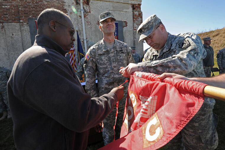 At Fort Mifflin, Charlie Company of the 103rd Engineers, a Pennsylvania National Guard unit based in West Philadelphia, is honored with the presentation of a Meritorious Unit Commendation Award for their service in Iraq in 2004-2005 on March 11, 2012. Here, soldiers (from left to right) 1st Sgt. Raymond Jamison; Brig. Gen. John Gronski and Capt. Michael Meads place the Meritorious Unit Commendation on the company guidon. (April Saul / Staff Photographer)
