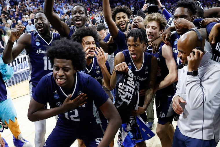Saint Peter's forward Clarence Rupert (left) celebrates with Saint Peter's Head Coach Shaheen Holloway and his teammates after they beat Purdue in a NCAA East Regional Sweet 16 game on Friday, March 25, 2022.