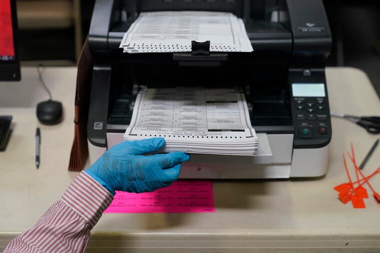 A county worker loads mail-in ballots into a scanner that records the votes at a tabulating area at the Clark County Election Department, Oct. 29, 2020, in Las Vegas.