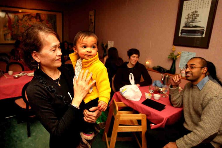 Ivy Fong, wife of Singapore Kosher Vegetarian Restaurant owner Peter Fong, holds Mira Shah, daughter of "nonpracticing HinJews" Peenesh Shah (right) and Elyse Fenton.