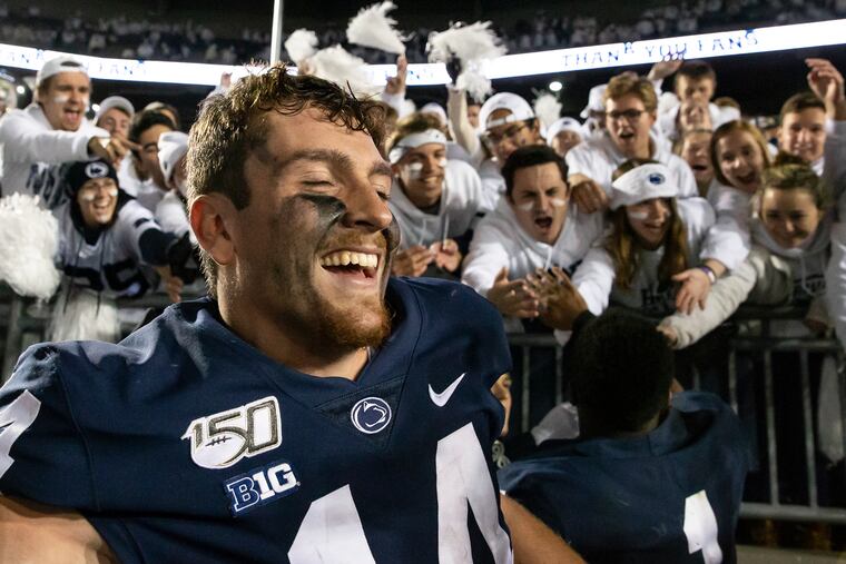 Penn State quarterback Sean Clifford celebrates with fans along with Penn State wide receiver KJ Hamler after their team defeated Michigan, 28-21, at Beaver Stadium