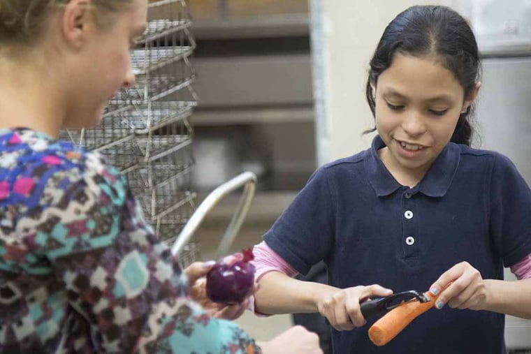 After school cooking class volunteer Jaimie Piotrowicz (left ) peels vegetables with Cayuga Elementary student Caytiria Esquilin, 10. The vegetables were roasted with the baked chicken and potatoes.