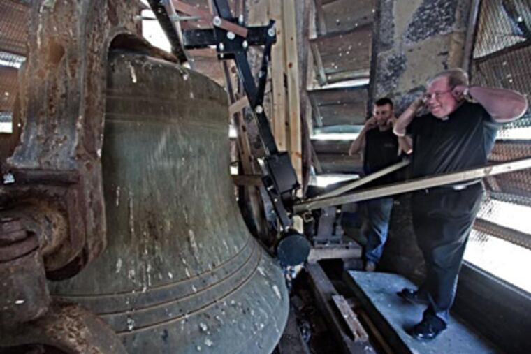 Fr. James A. Lyons (right), and John Woods, maintenance man for St. John the Baptist, cover their ears as the church bell chimes three times to mark 3 p.m. (File Photo / Staff)