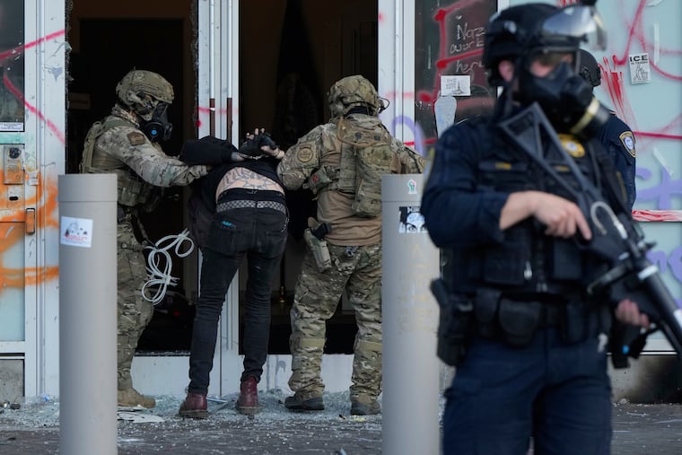 Federal officers detain a man outside the U.S. Immigration and Customs Enforcement building during a protest last year in Portland, Ore.
