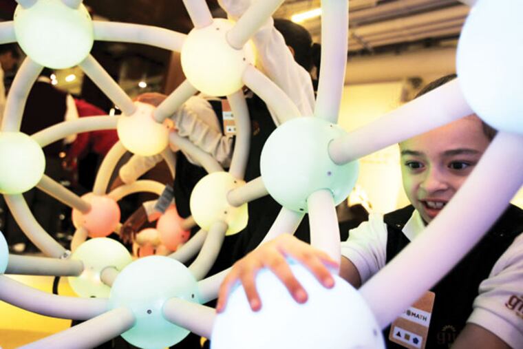 Girls Preparatory student Faith Guzman, 7, tried out an interactive display at the new National Museum of Mathematics in New York, Monday, Dec. 17, 2012. The museum is aimed at kids aged 8 to 13, and curators have given the place a playground feel. The 40 exhibits include a "wall of fire" made up of laser lights that teaches kids about geometry and a square-wheeled tricycle that still manages to produce a smooth ride thanks to a wavy track. (AP Photo/Seth Wenig)