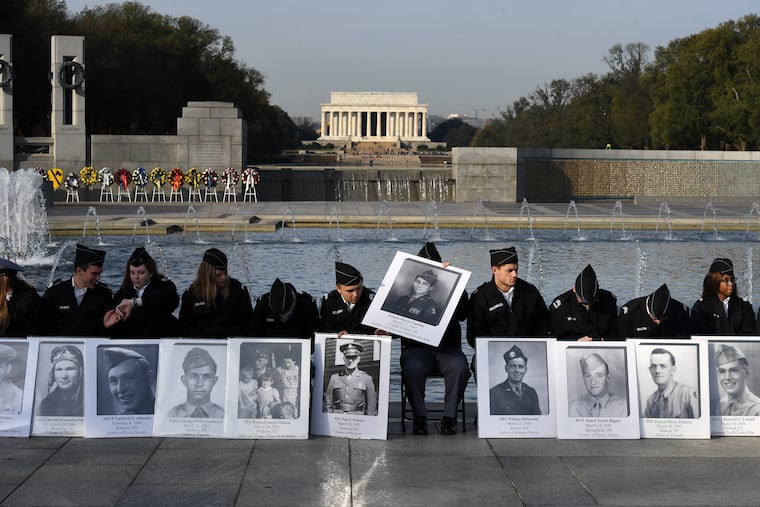 Members of the Georgia Military College Prep School in Milledgeville, Georgia, hold photos of fallen World War II soldiers during a Veterans Day ceremony at the World War II Memorial in Washington on Monday. The day, the author writes, is an especially poignant time to remember the needs of those veterans who have trouble accessing needed mental health services. Washington Post photo by Matt McClain.