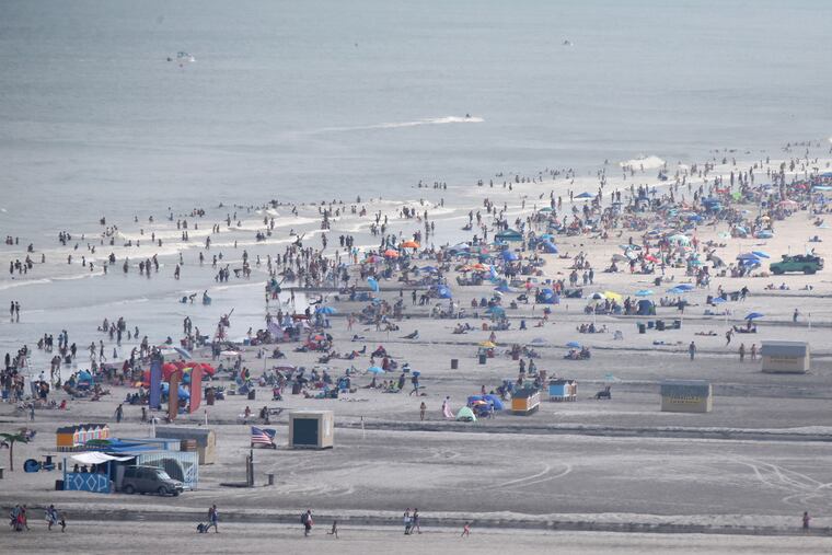 In this photo taken with a telephoto lens, people sit in groups on the beach in Wildwood, N.J., in 2020.