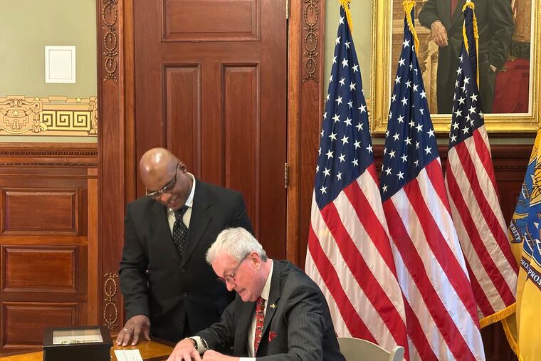New Jersey Gov. Phil Murphy signs a pardon for Abdur Azam, left, at his statehouse office in Trenton.