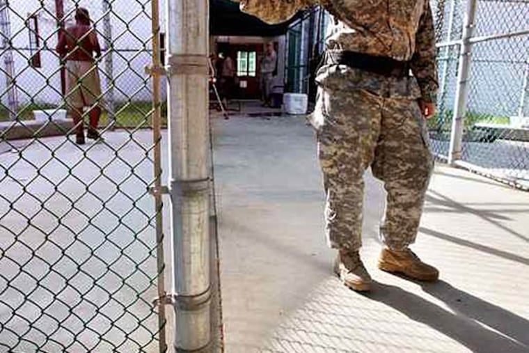 A guard stands near a fence as a Guantanamo detainee, (left) jogs inside the exercise yard at the detention center at the U.S. Naval Base in Guantanamo Bay, Cuba. (FILE)