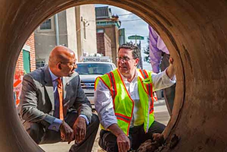 Mayor Michael Nutter and Water Department Commissioner Howard Neukrug examine the pipe that was taken out of the wash out hole on the corner of 21st and Bainbridge July 30 2012. (ELISE WRABETZ / Staff Photographer)