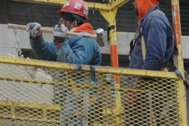 Workers demolish the facade of one of the buildings in the Convention Center's way.