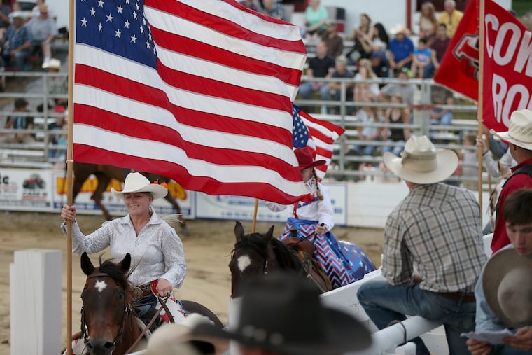 Katy Harris Griscom, left, carries the American flag during the grand entry on this year's opening night of the annual Cowtown Rodeo in Pilesgrove, N.J., on Saturday, May 26, 2018. Griscom and her husband, RJ, took over rodeo operations this year from her father. The weekly rodeo is now in its 64th consecutive year.