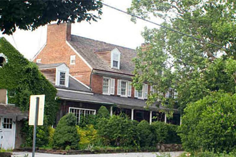 Nearly hidden by overgrown shrubbery and trees, the Red Rose Inn in Penn Township is set for a foreclosure auction July 21. (ED HILLE / Staff Photographer)